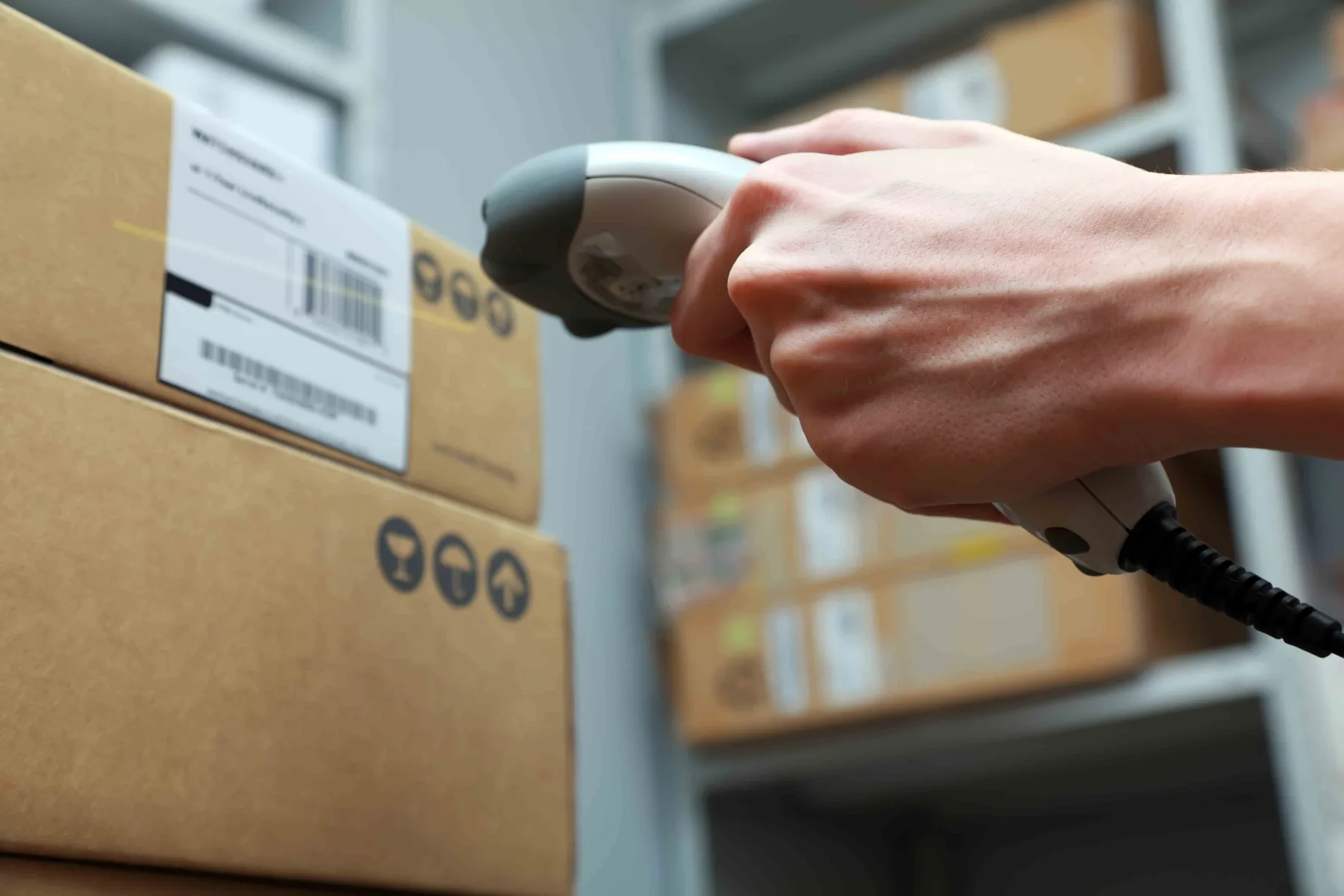 Warehouse worker scanning a barcode label on a cardboard shipping box for fulfillment tracking